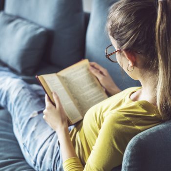Kvinna sitter i en soffa och läser en bok