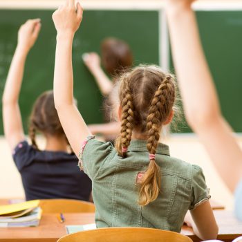 Elever i ettklassrum räcker upp handen.
